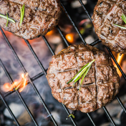 Beef Burgers On Grill With Flames From Charcoal, Overhead View