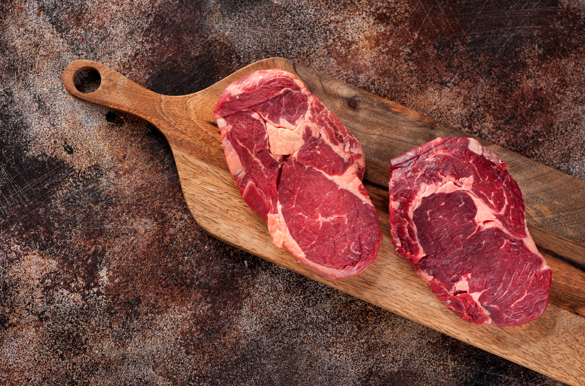 Raw Ribeye Steak On A Wooden Board, Top View